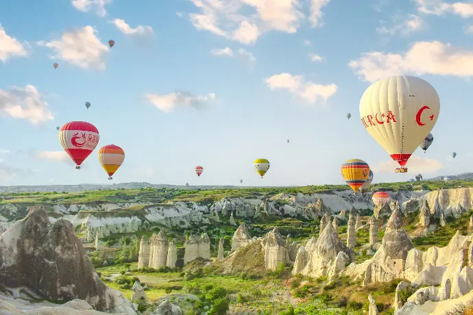 a group of hot air balloons flying over a valley